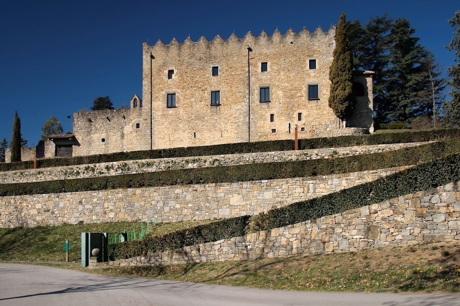 Un castillo de piedra histórico con múltiples torres y un jardín bien cuidado.
