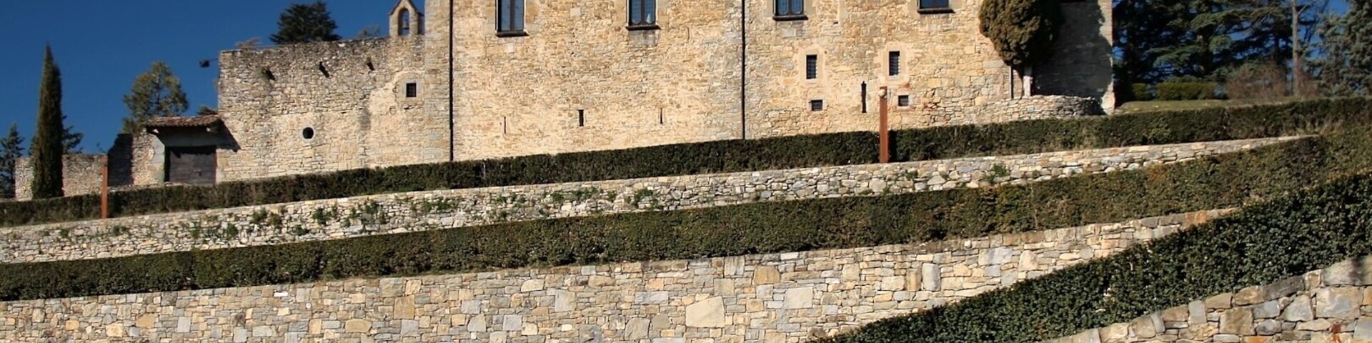 Un castillo de piedra histórico con múltiples torres y un jardín bien cuidado.