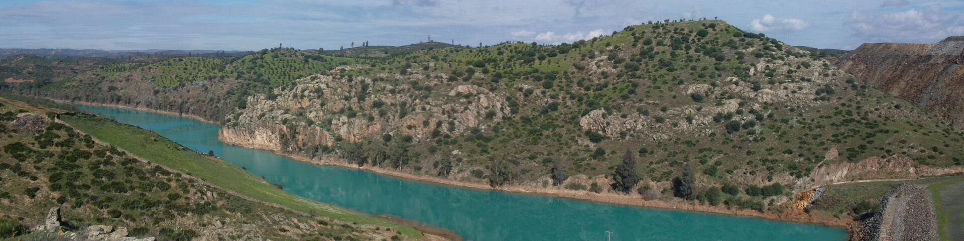 Rio Agrio a la altura del casco municipal de Aznalcóllar que queda a la izquierda de la imagen y fuera de ella. A la derecha están las escombreras de las antiguas minas de pirita. El color turquesa es debido a la contaminación residual que proviene de las escorrentias de las escombreras.
