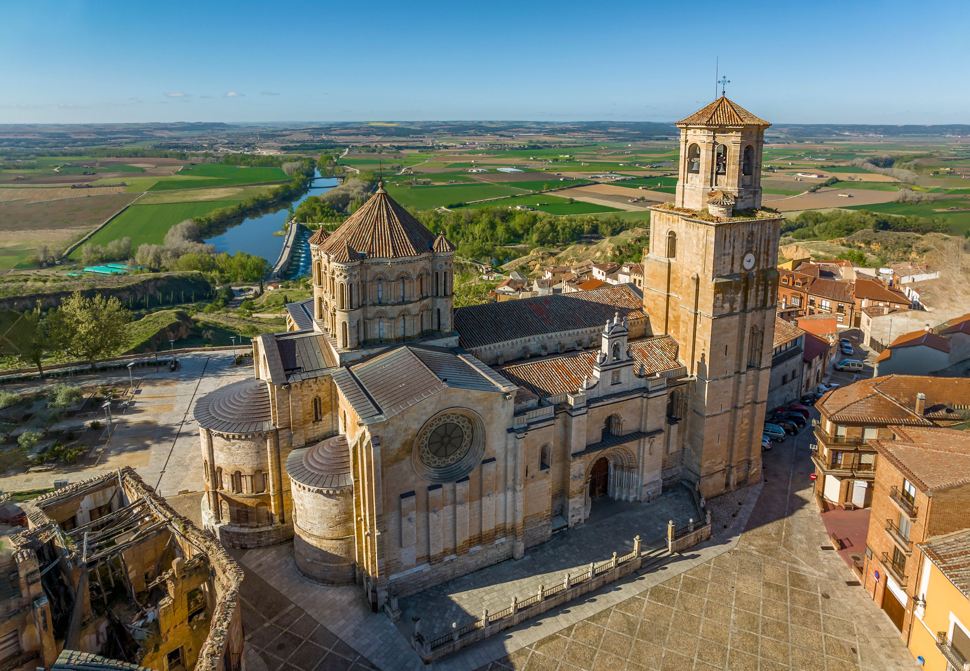 Una iglesia histórica con un campanario y un río al fondo.