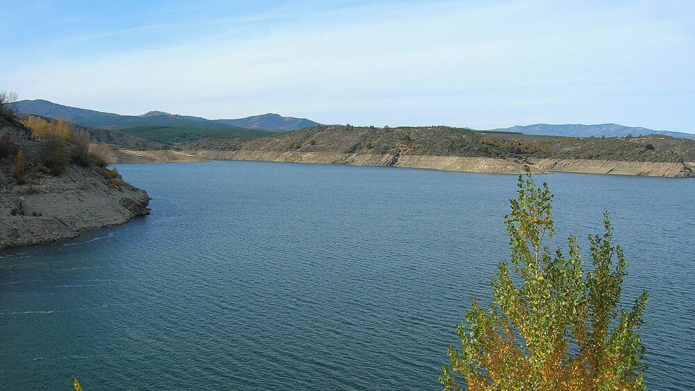 Un lac paisible, entouré de collines et d’une végétation clairsemée.