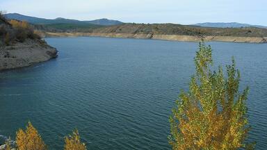A calm lake surrounded by hills and sparse vegetation.