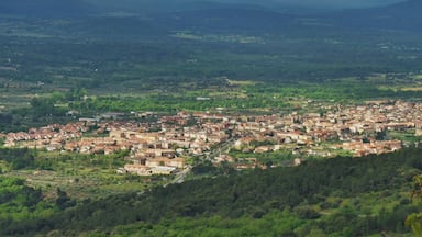 A town nestled in a valley with a backdrop of mountains and a cloudy sky.