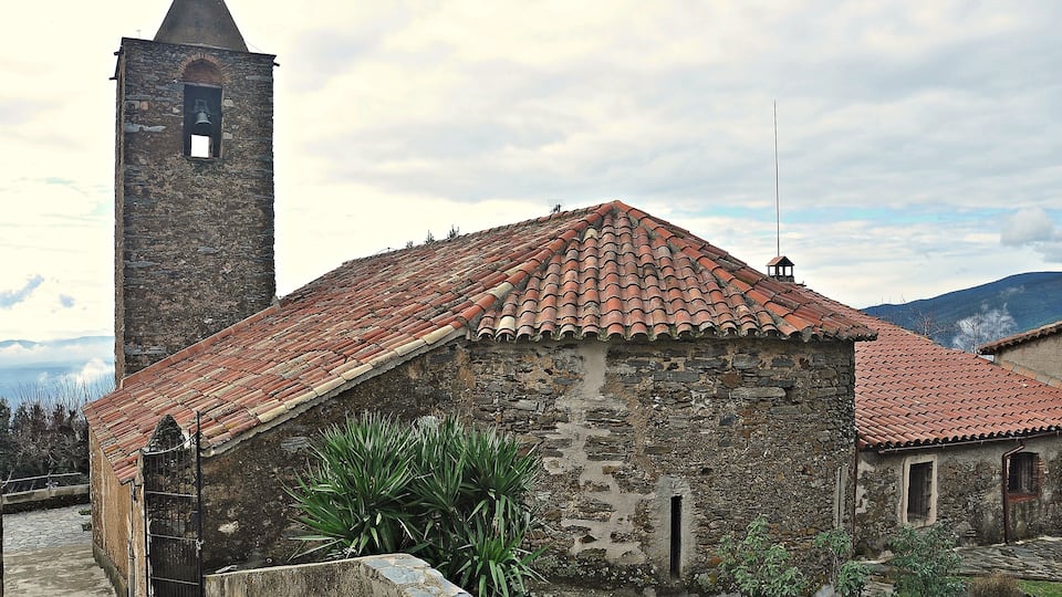 A stone church with a bell tower and red-tiled roof.