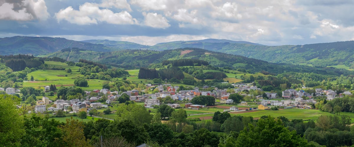 A town nestled in a valley with rolling hills and a mix of residential and commercial buildings.