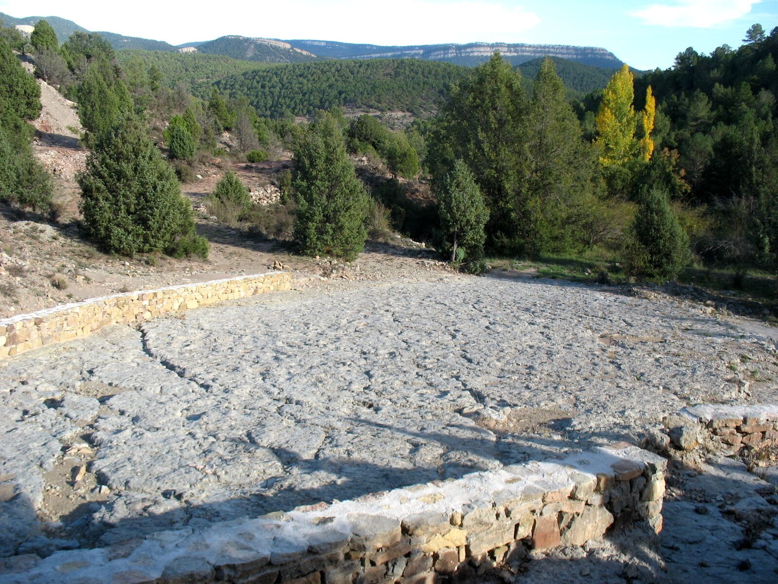 A rocky amphitheater surrounded by forested hills.