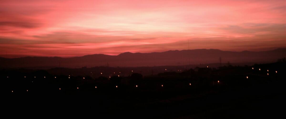 A sunset over a cityscape with a pink and purple sky.
