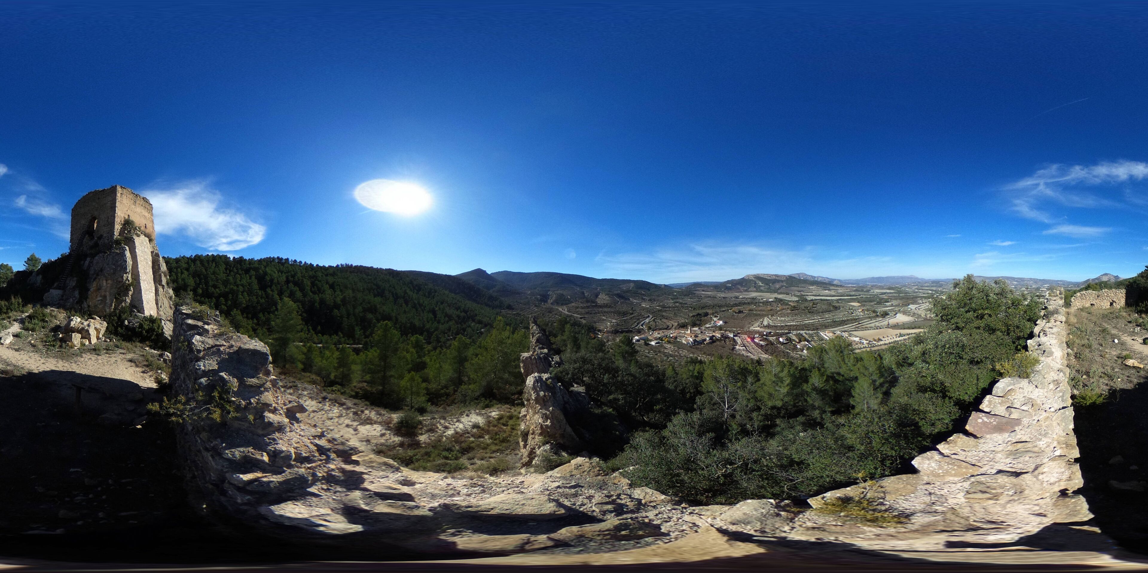 A mountainous landscape with a prominent rock structure and a clear blue sky.