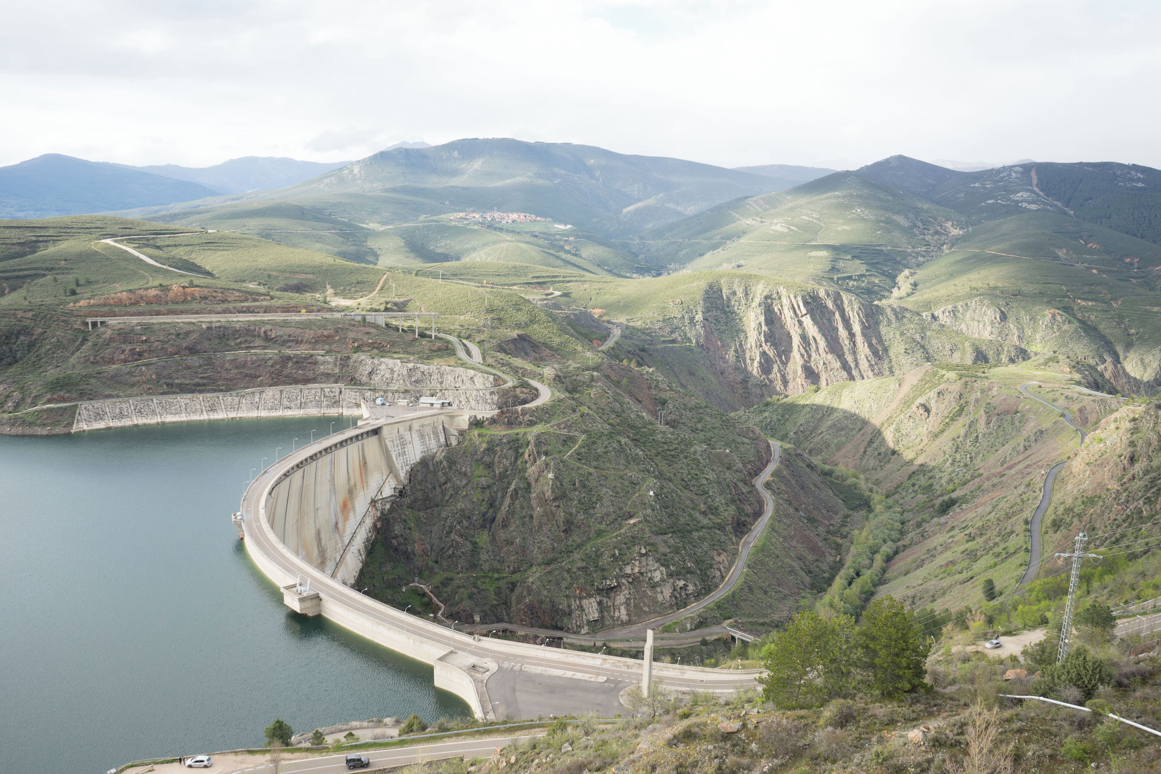 A dam with a winding road and a valley.