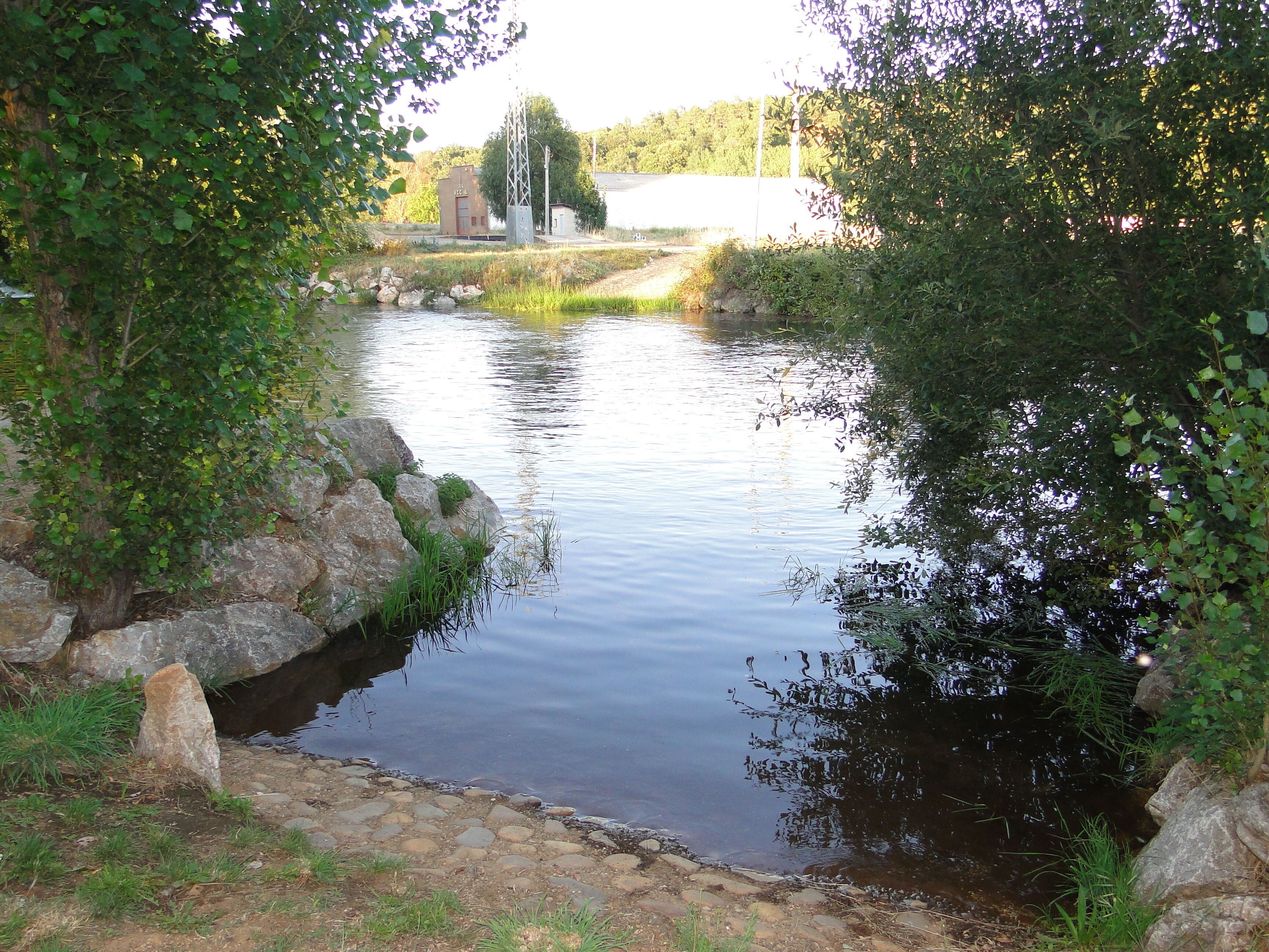 A calm river with rocks and greenery on the banks.