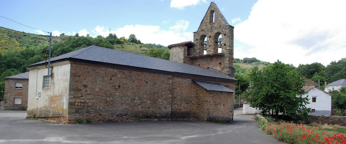 A stone church with a bell tower and a paved road in front.