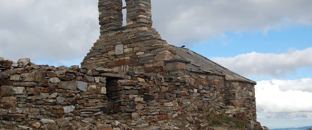 A stone ruin with a pointed roof and a small door.