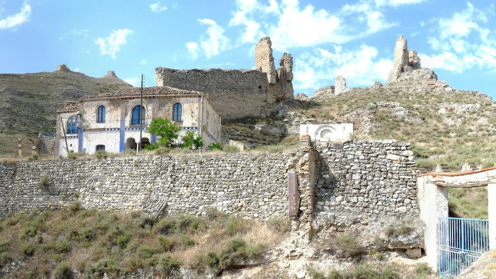 Une ancienne construction en pierre, en partie en ruines, et un petit bâtiment doté de fenêtres en arc.