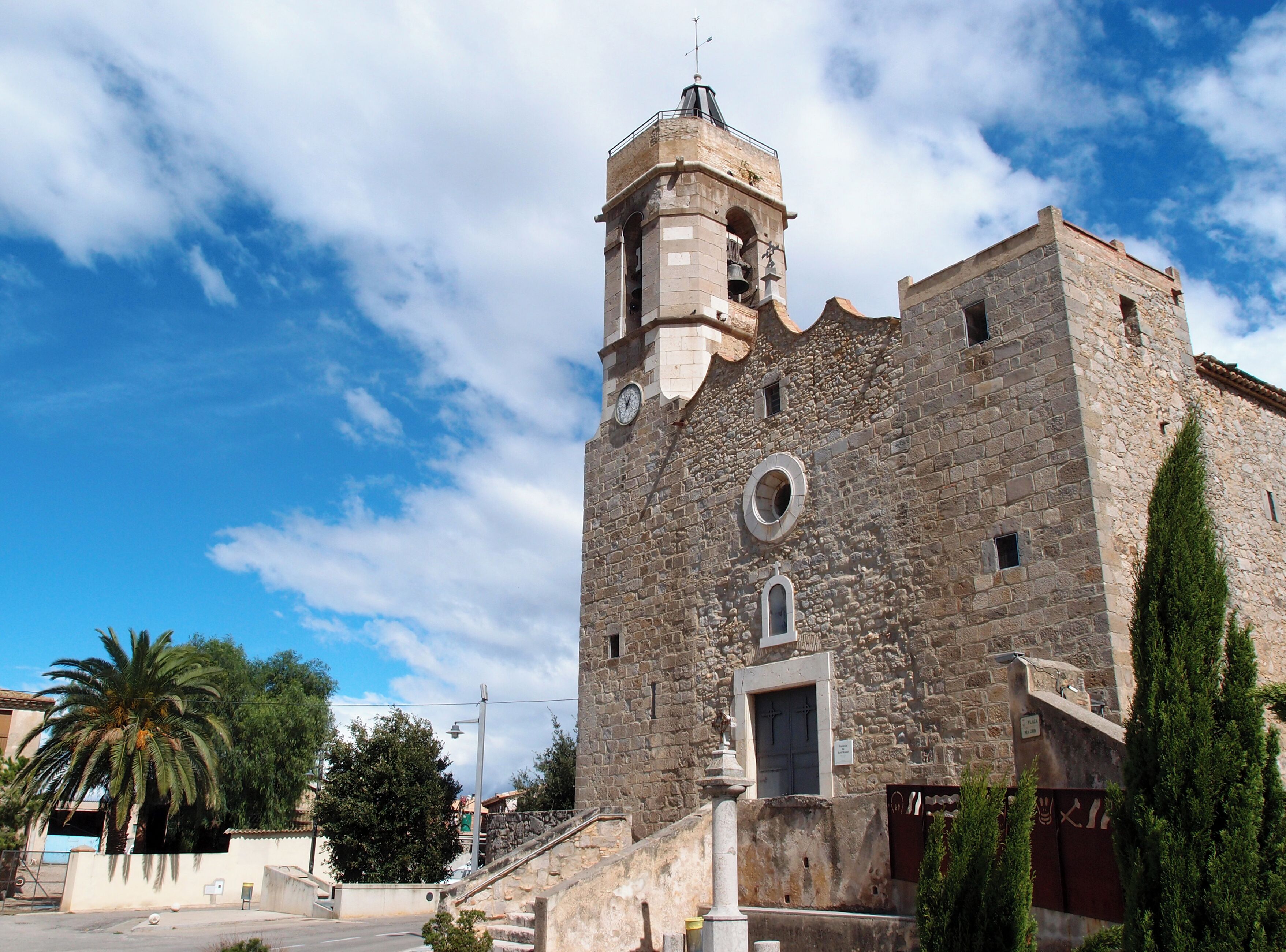 A historic stone building with a bell tower and a circular window.