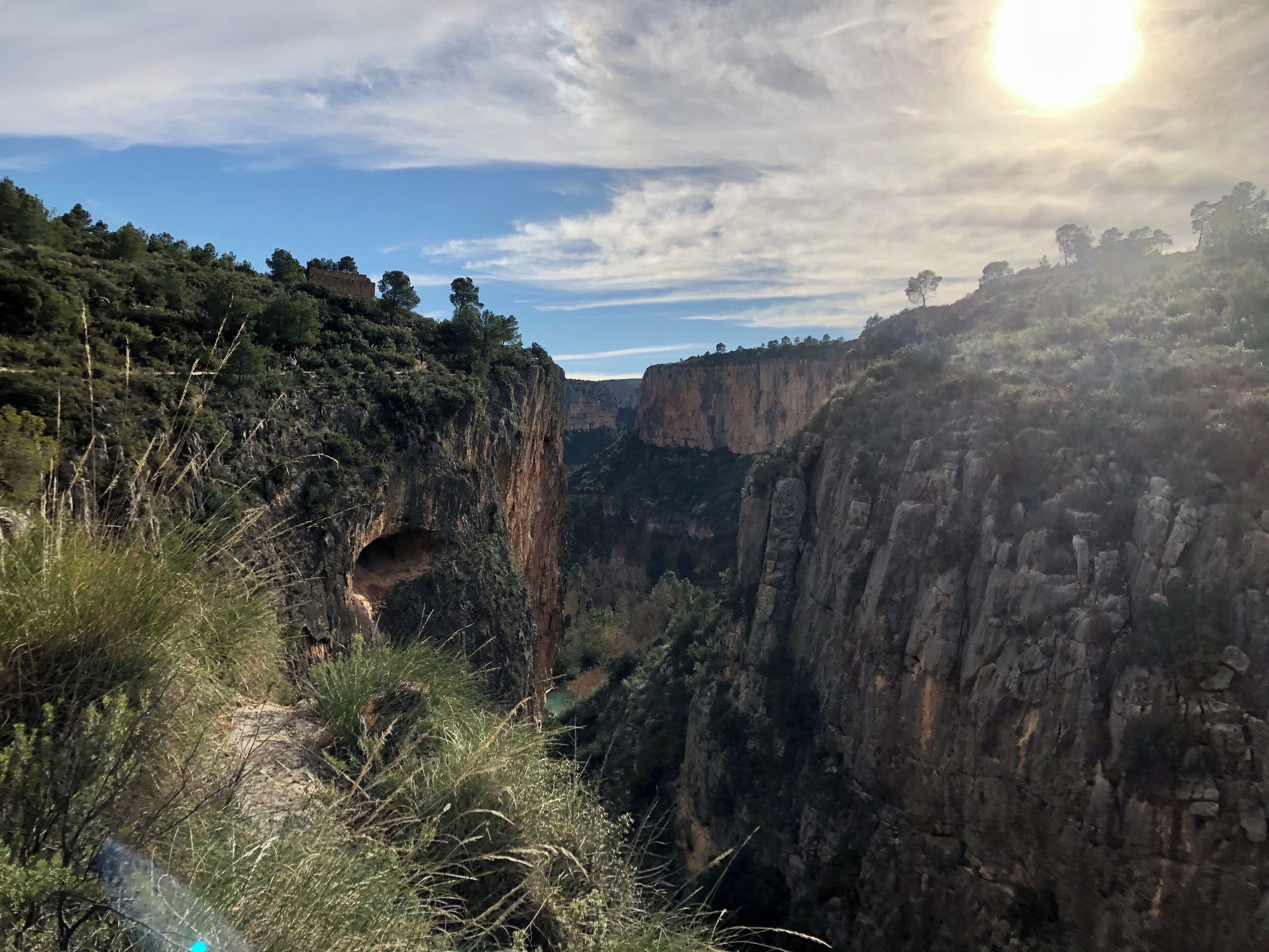 A canyon with steep cliffs and a small cave entrance.