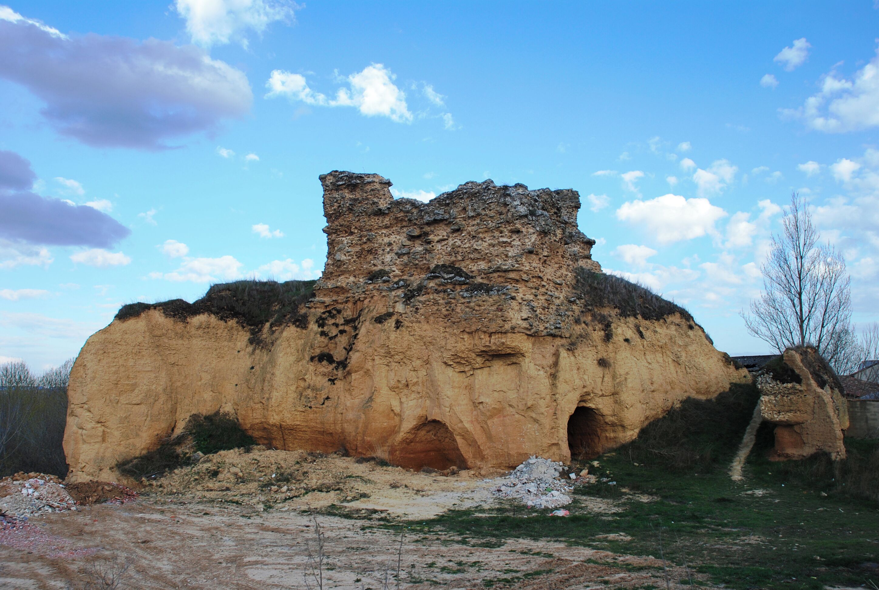 A large rock formation with a cave entrance and a smaller cave to the right.
