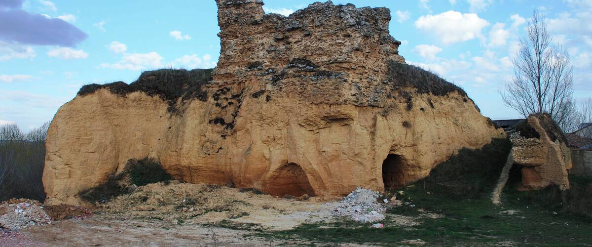 A large rock formation with a cave entrance and a smaller cave to the right.