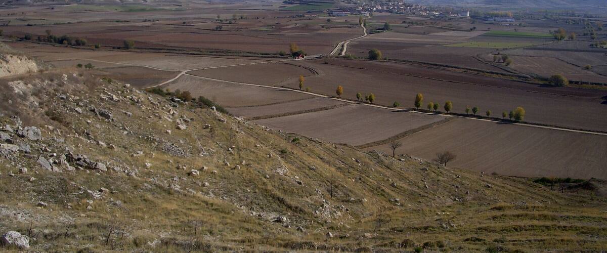 A rural landscape with rolling hills, fields, and a distant village.