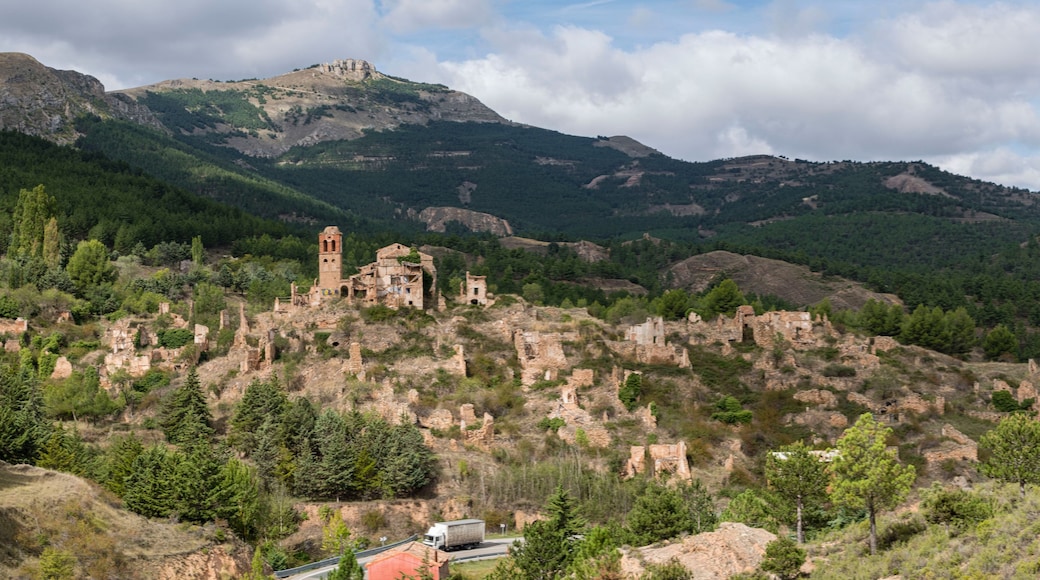 Paisatge montanyós amb ruïnes i una torre.