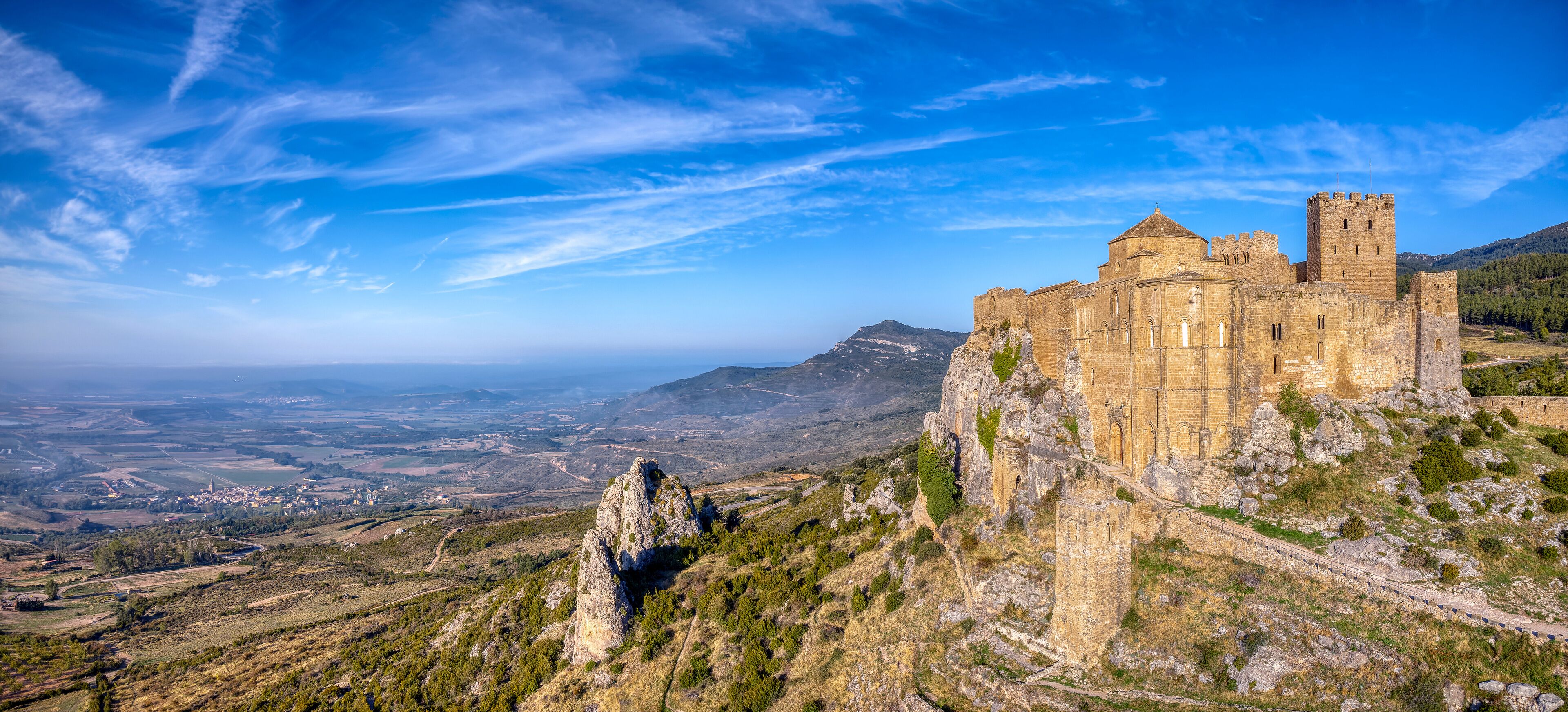 A historic stone castle on a hill overlooking a valley.