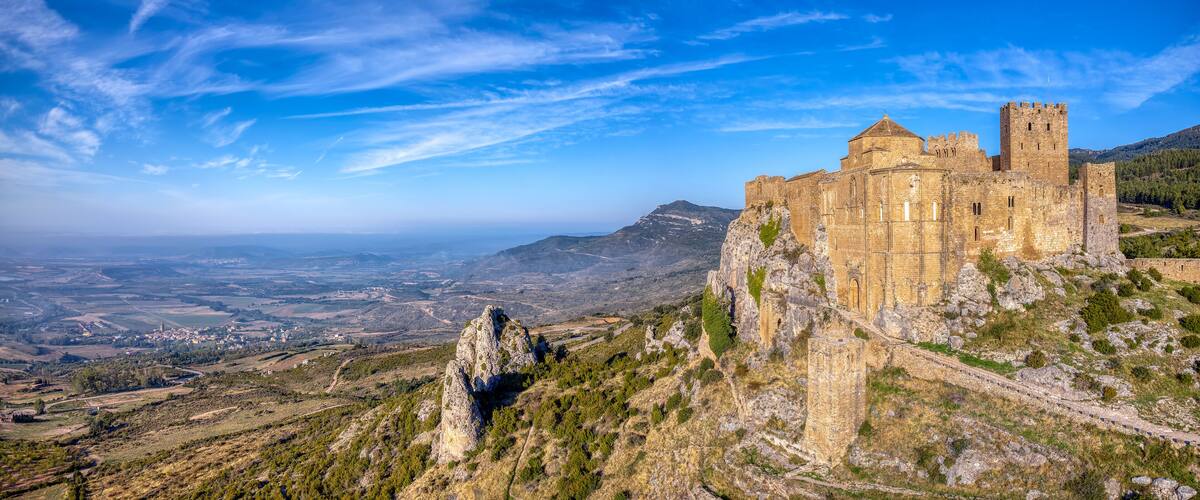A historic stone castle on a hill overlooking a valley.