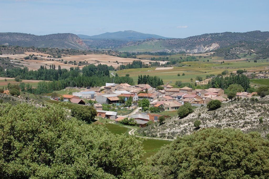 A village nestled in a valley surrounded by hills and fields.