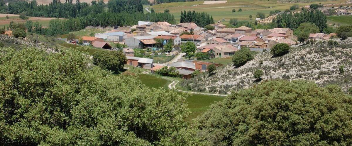 A village nestled in a valley surrounded by hills and fields.