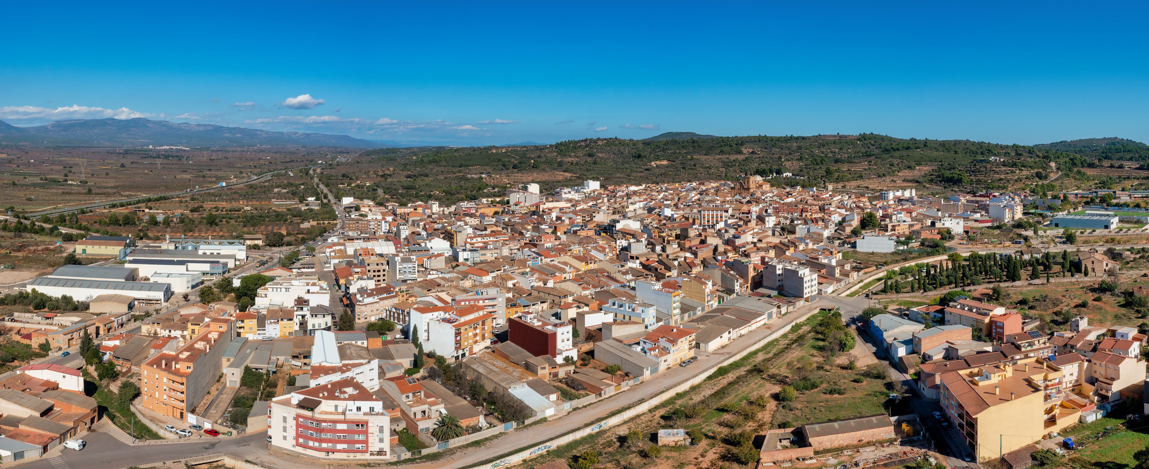 A densely populated town with a mix of residential and commercial buildings, surrounded by hills and mountains.