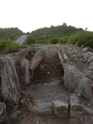 An ancient stone structure with a central passageway surrounded by large boulders.