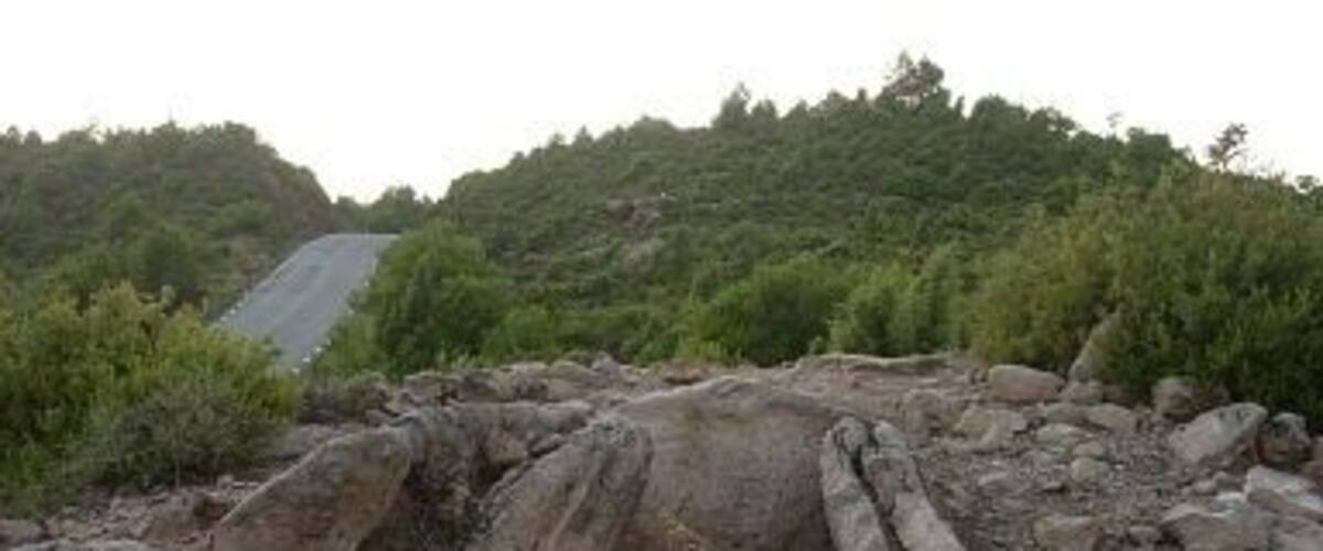 An ancient stone structure with a central passageway surrounded by large boulders.