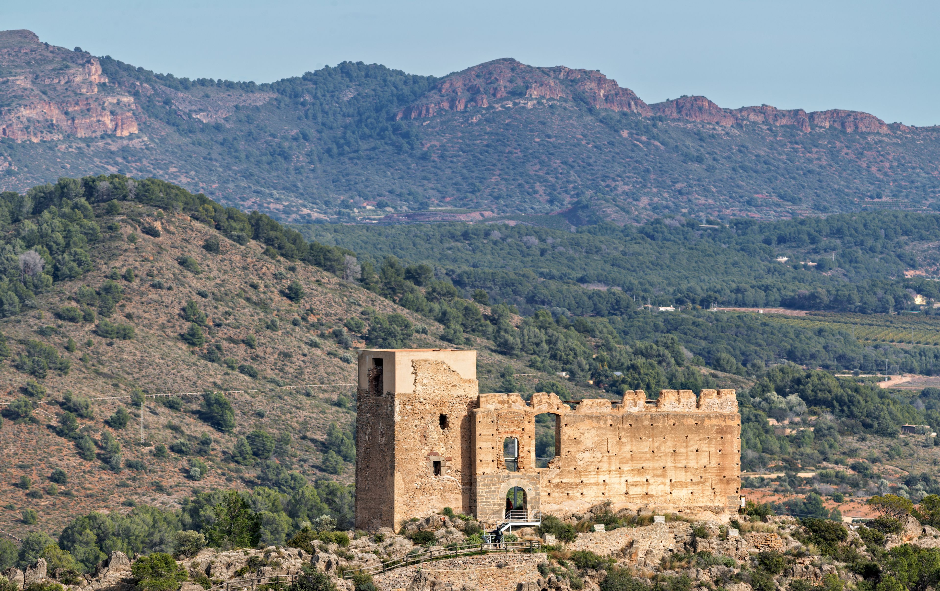 Une tour de pierre historique, dressée au milieu d’un paysage montagneux à la végétation clairsemée.