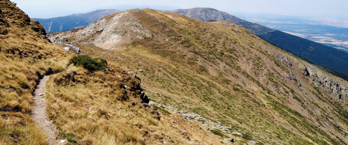 A mountainous landscape with a dirt path leading to a peak.
