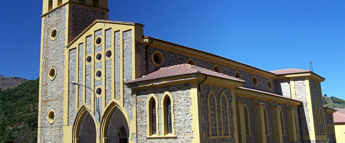 A church with a bell tower, arched windows, and a stone facade.
