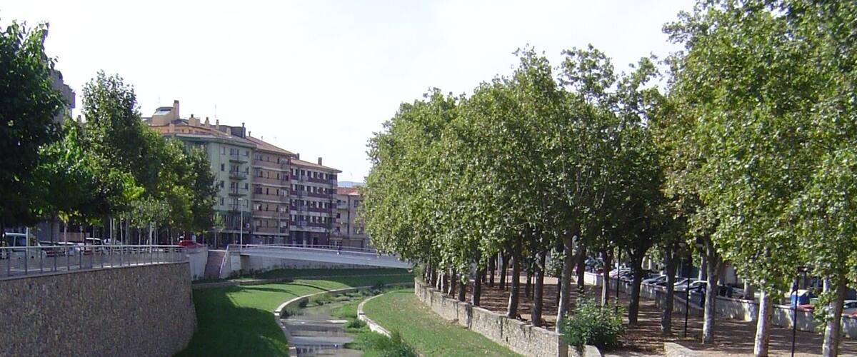A canal with a stone wall on one side and a grassy embankment on the other.