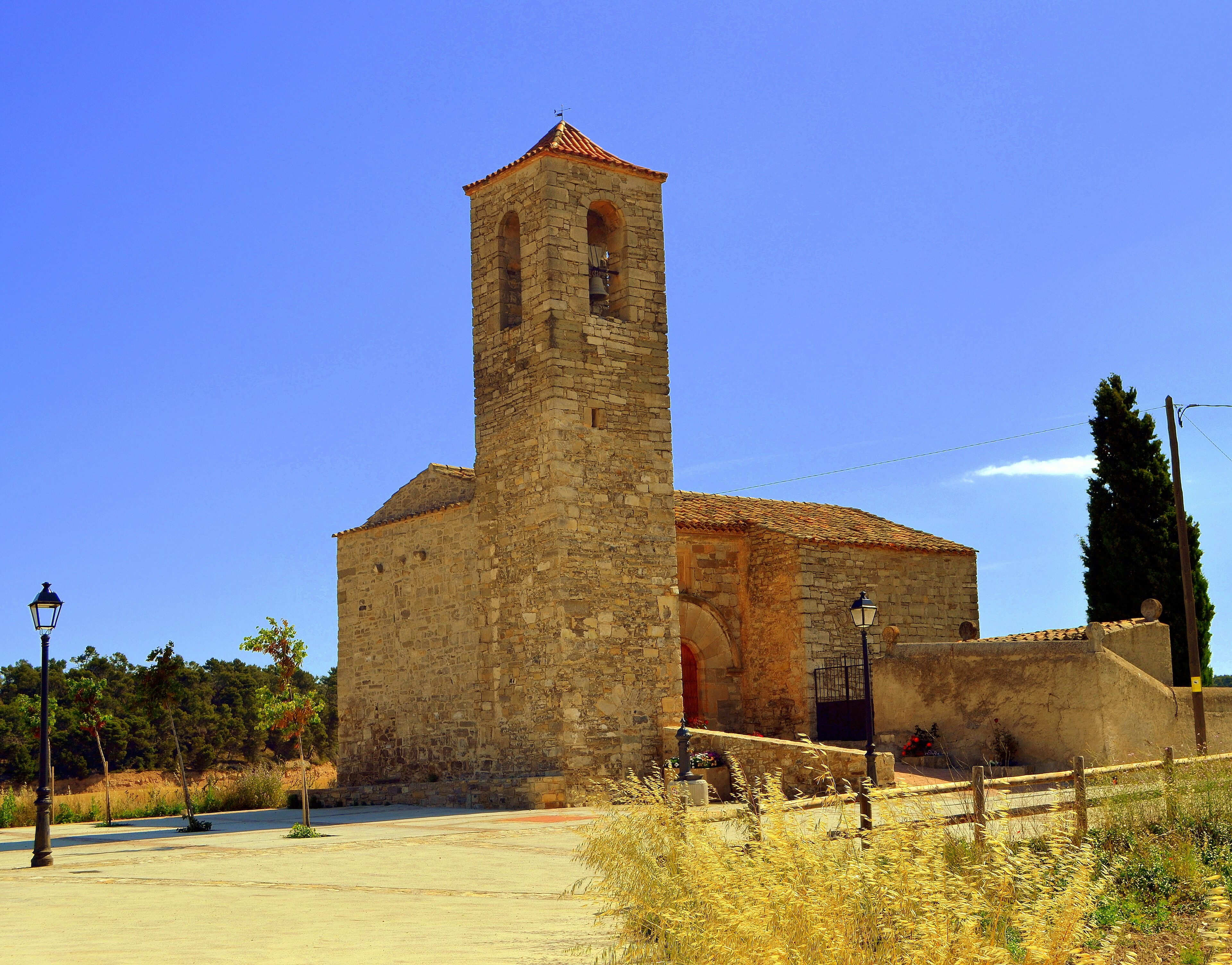 A historic stone church with a bell tower and a red-tiled roof.