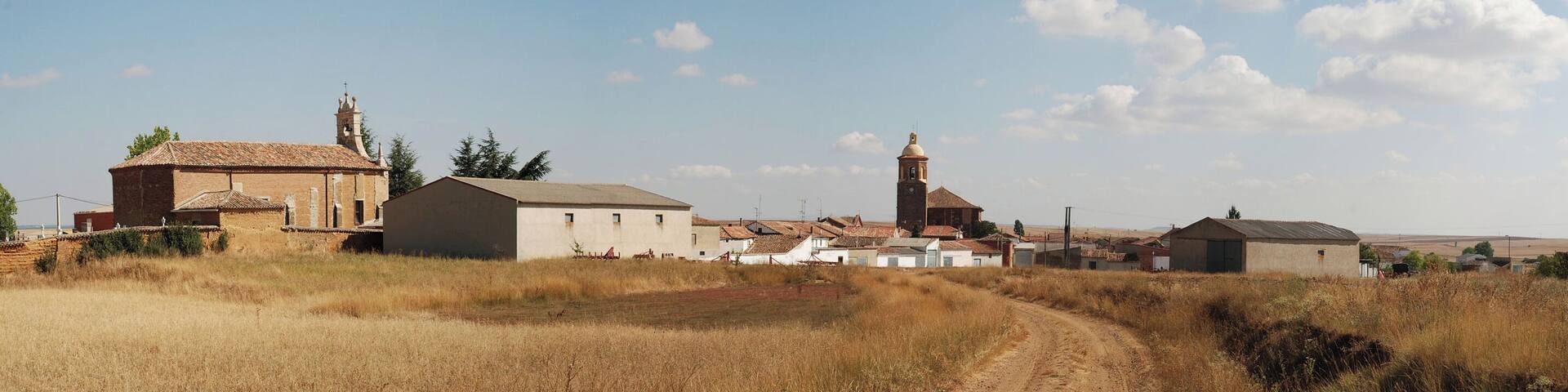 A rural village with a church, a bell tower, and several buildings.
