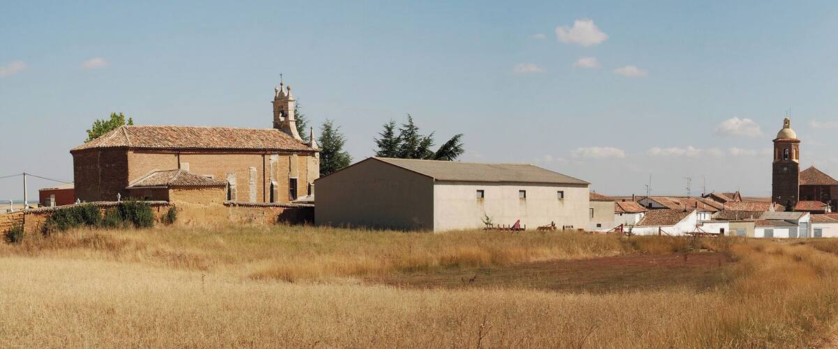 A rural village with a church, a bell tower, and several buildings.