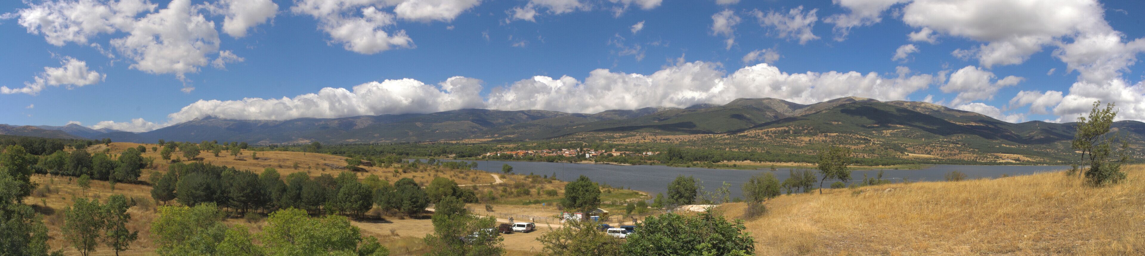 A lake surrounded by mountains, a small town, and a forested area.
