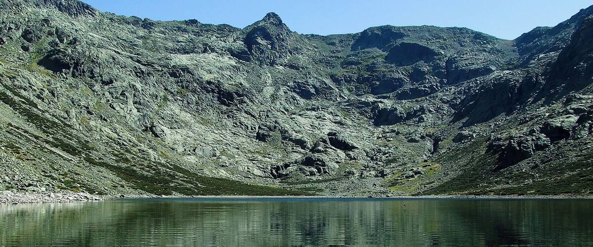 A clear mountain lake surrounded by rocky terrain.