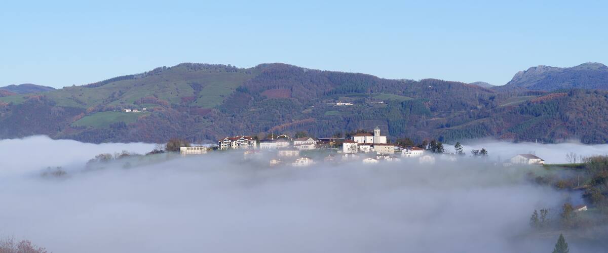 A village nestled in a valley with mist-covered mountains in the background.