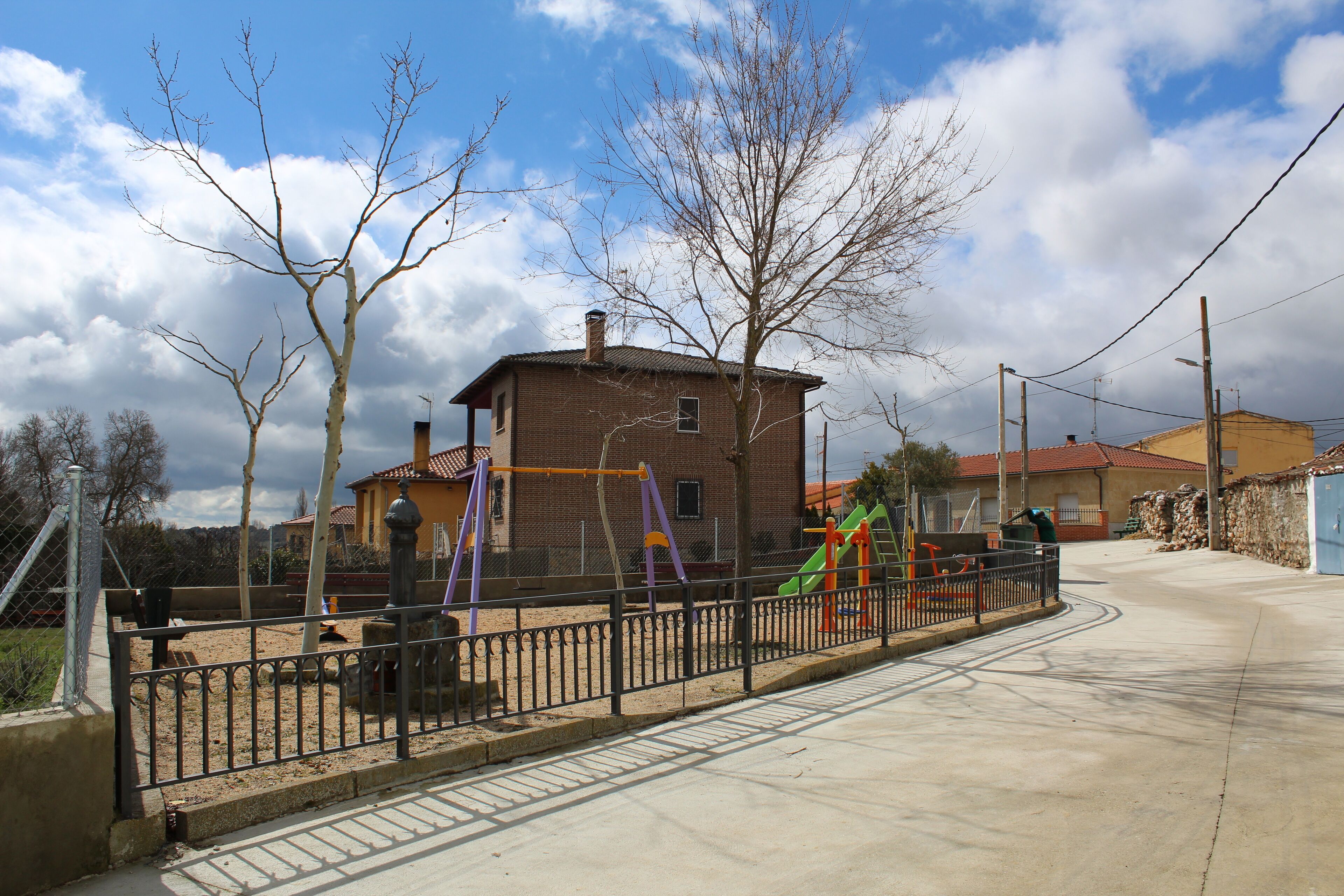 A playground with swings and slides, a brick building, and a clear sky.