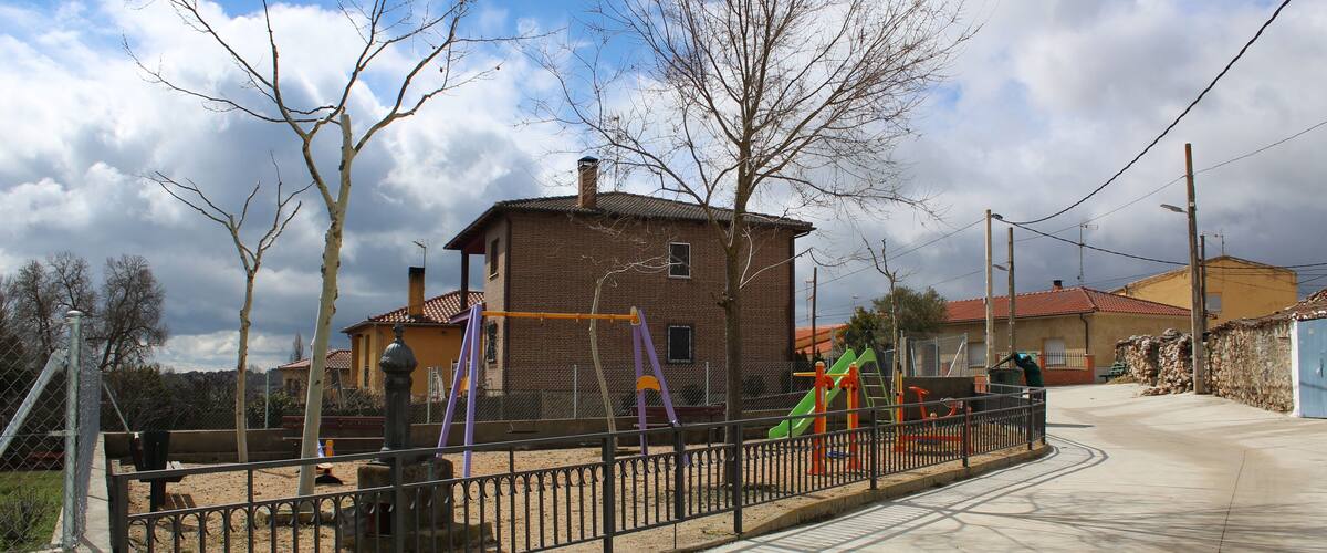 A playground with swings and slides, a brick building, and a clear sky.