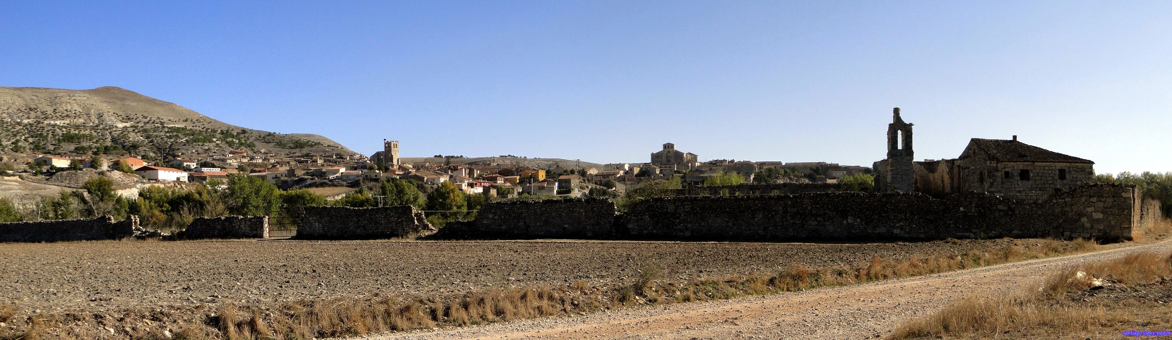 A historic town with stone walls, a church, and a tower.