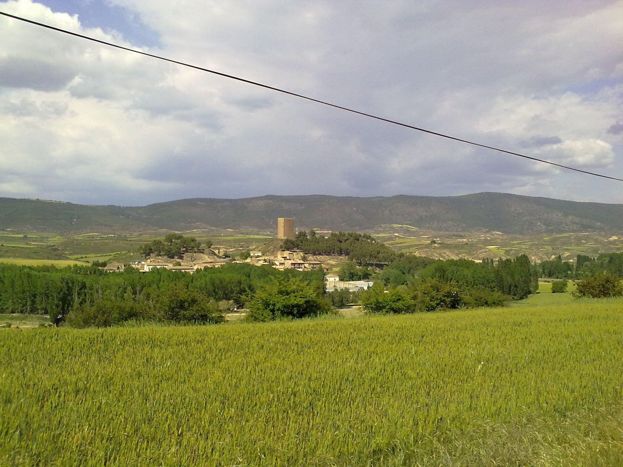 A rural landscape with a tower, fields, and distant hills.
