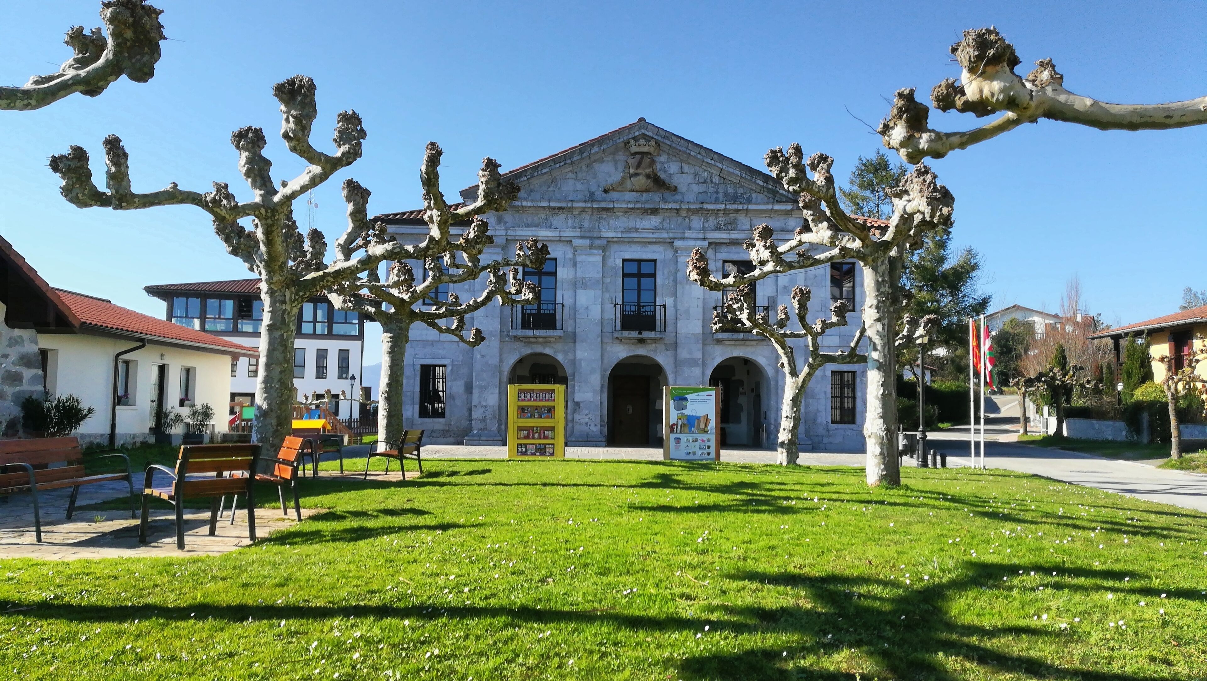 A historic building with classical architecture, surrounded by well-maintained grass and trees.