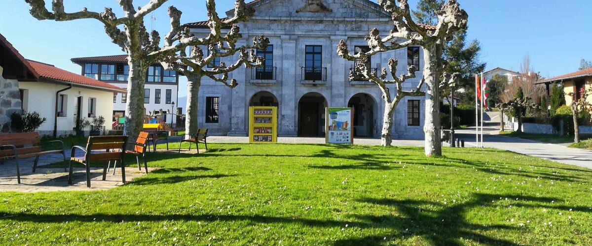 A historic building with classical architecture, surrounded by well-maintained grass and trees.