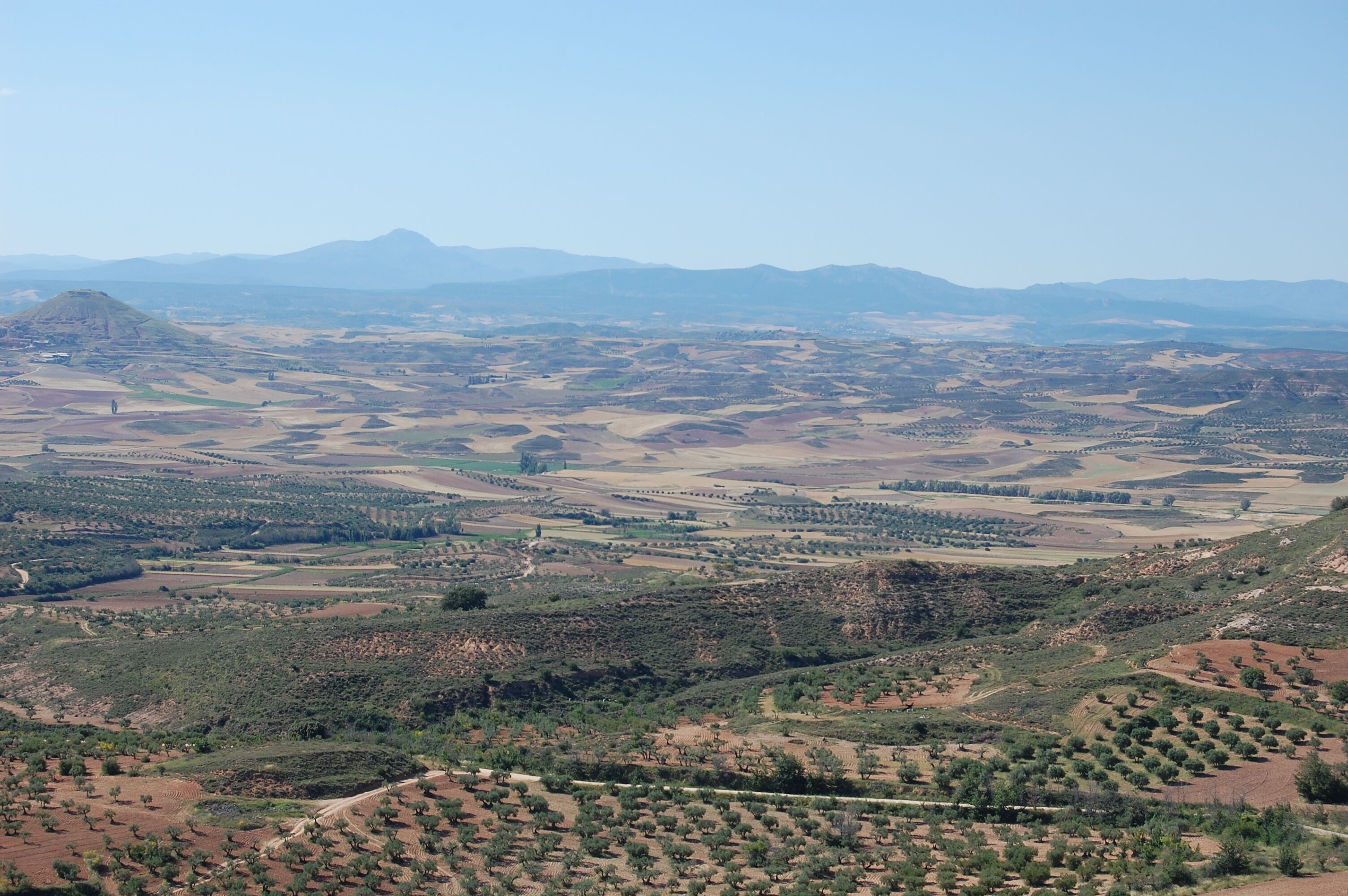 A vast landscape with rolling hills, fields, and sparse vegetation.