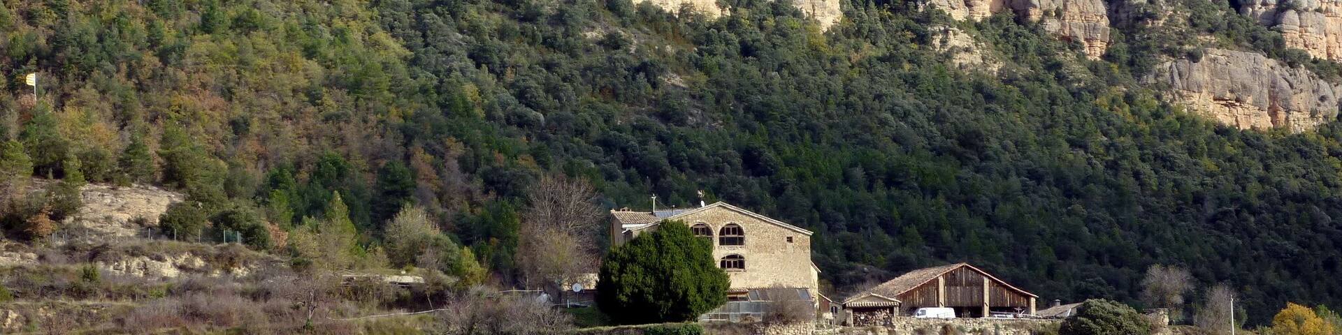 A rugged mountain landscape with a stone building and a wooden structure at its base.