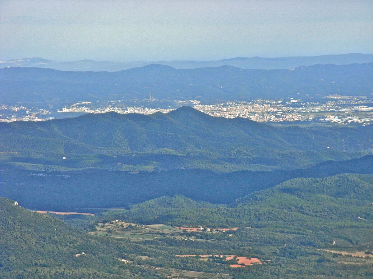 Girona, des del Far, a 25 km de distància. Al fons, a l'esquerra de tot, La Bisbal.