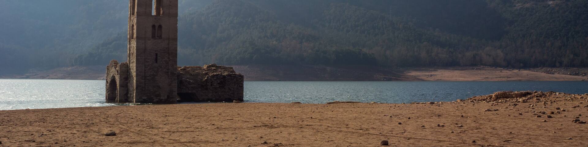 A coastal landscape with a ruined tower and a mountain in the background.